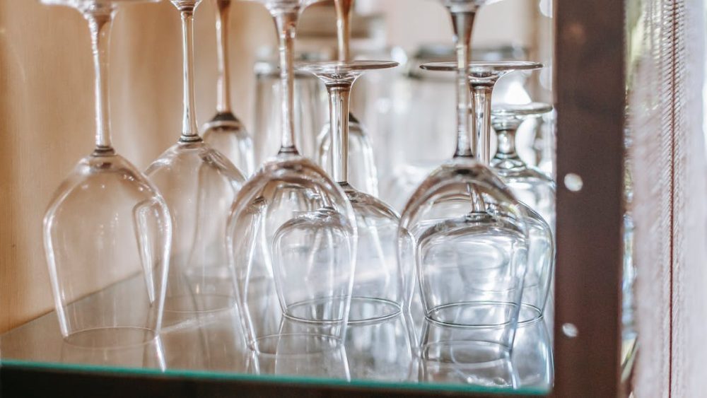 many-wineglasses-placed-upside-down-on-glass-shelf-in-cupboard-in-light-modern-restaurant